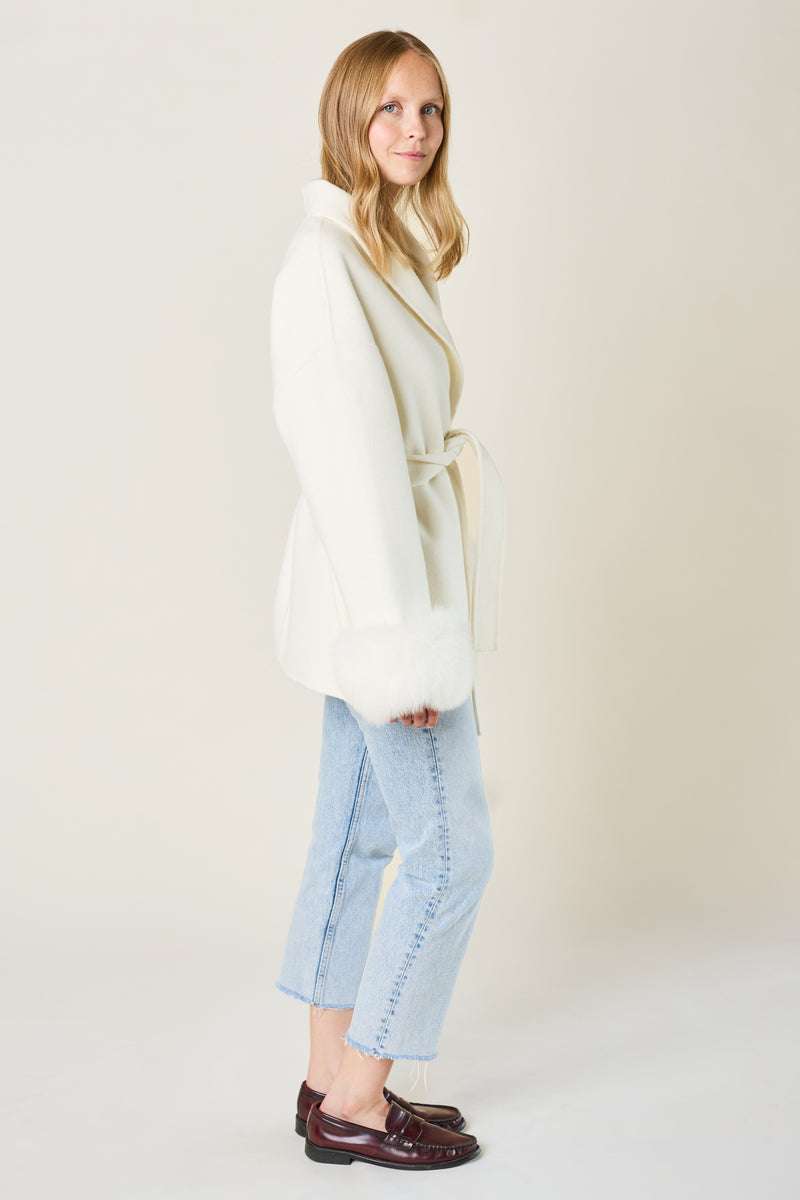 Woman wearing a white coat with detachable fox fur cuffs and cashmere fabric