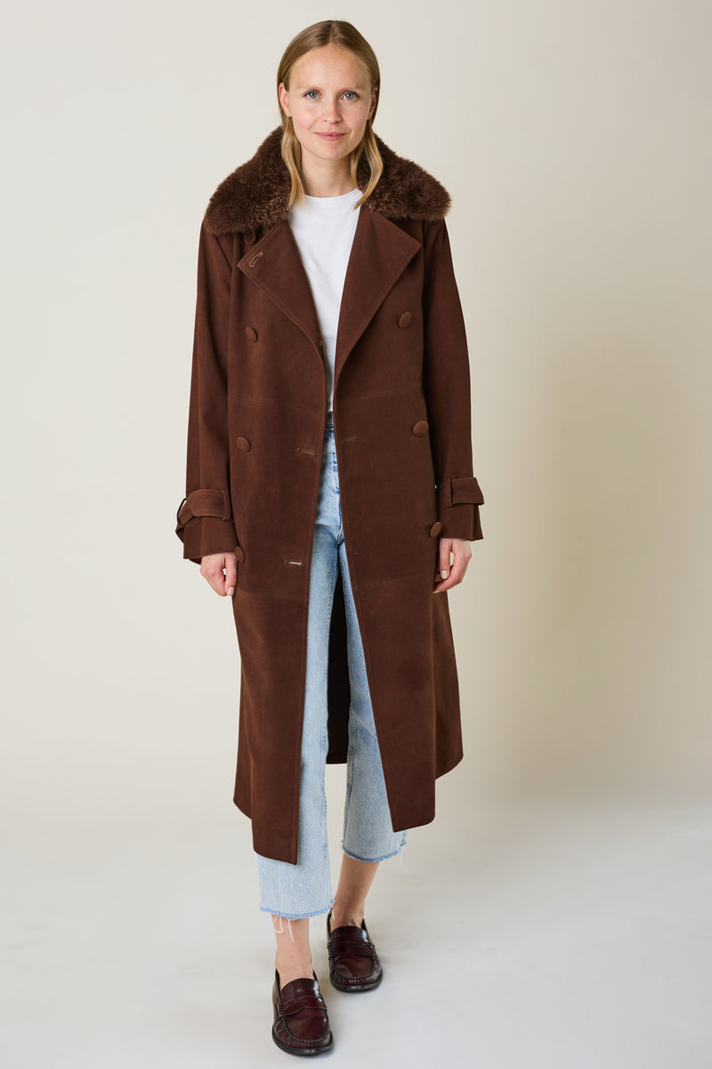 Woman wearing a brown coat in suede leather with brown mongolian shearling fur on collar 