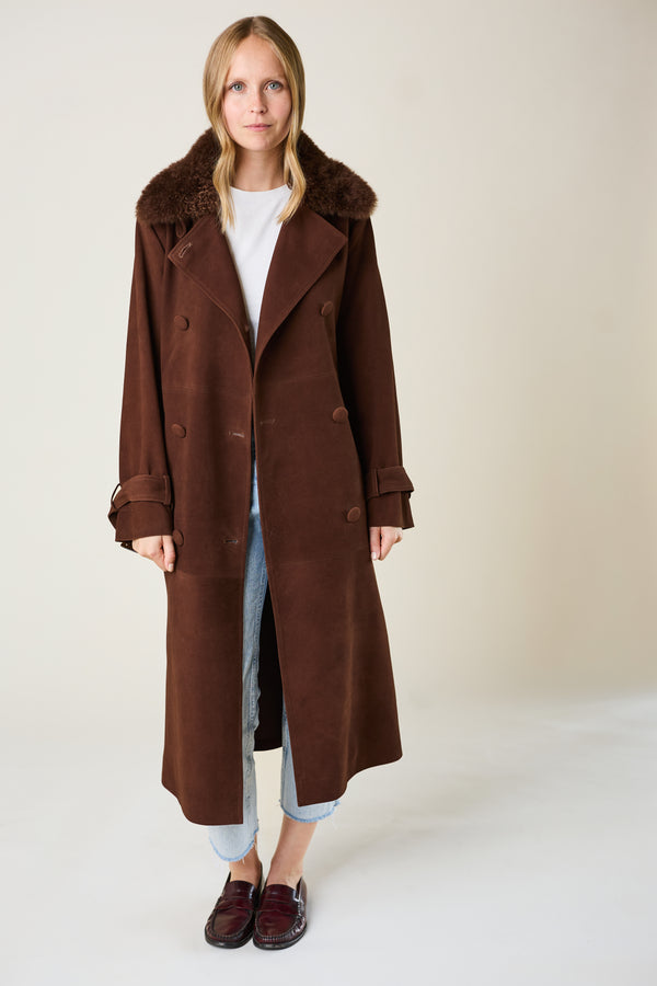 Person wearing a brown coat on a plain background