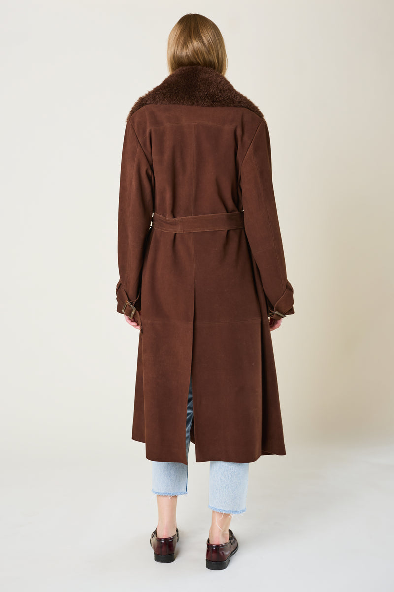 Person wearing a brown coat with fur collar on a white background