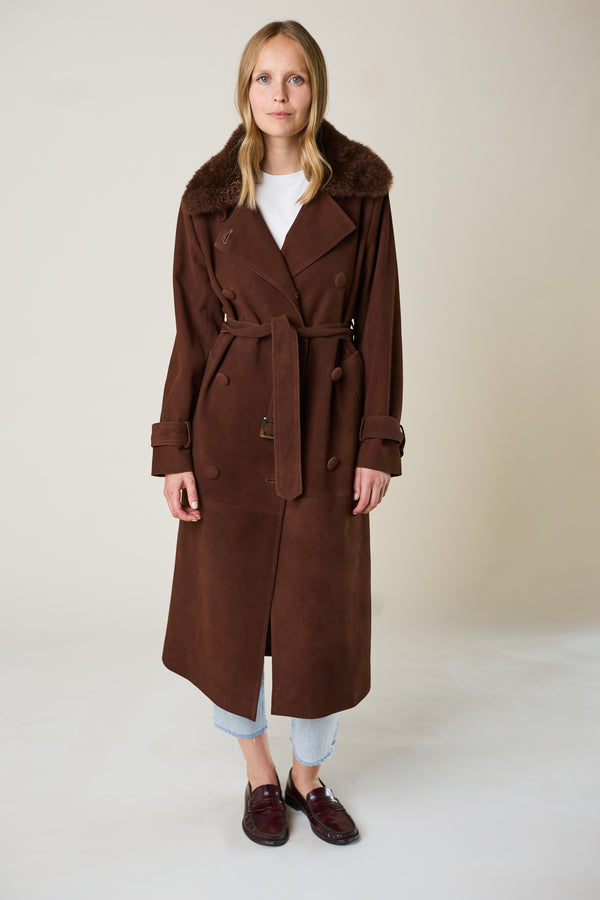 Woman wearing a brown trench coat on a plain background