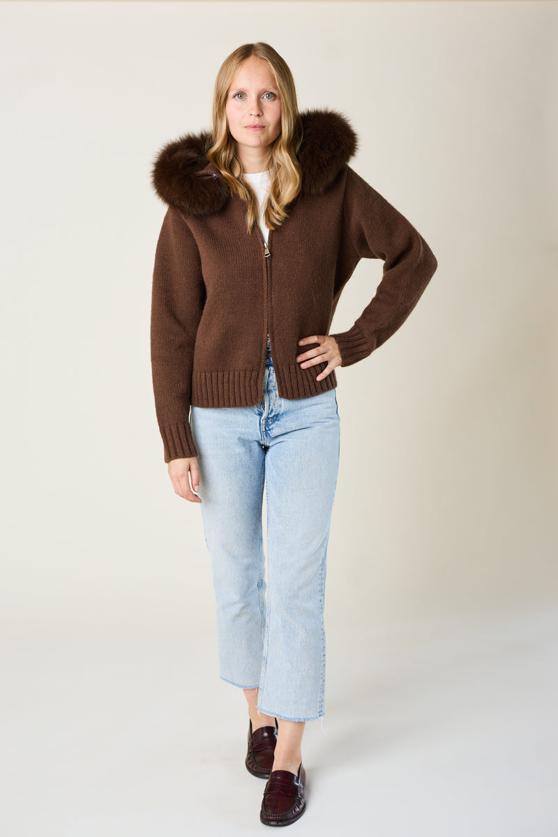 Woman wearing a brown cardigan with fur trim on a white background